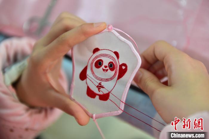 圖為一名小學(xué)生正在繡制2022年北京冬奧會(huì)吉祥物“冰墩墩”形象?！∮髟屏?攝
