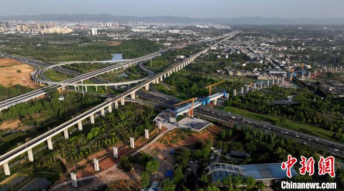 航拍正在建設的跨越成都繞城高速公路連續(xù)梁施工現(xiàn)場，旁邊依次為已運營的成渝高速鐵路和機場高速公路?！⒅铱?攝