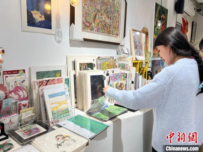 圖為藝術品商店內，顧客挑選插畫作品?！＄婌?攝