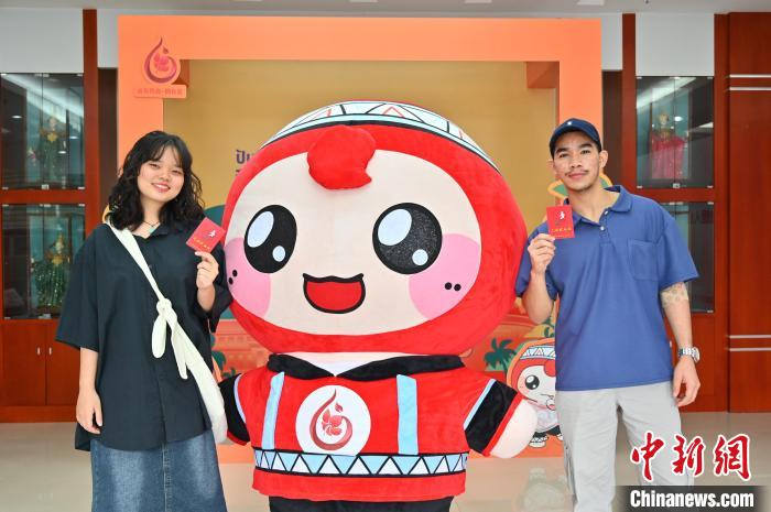 圖為泰國(guó)留學(xué)生手持獻(xiàn)血證與人偶合影。　俞靖 攝