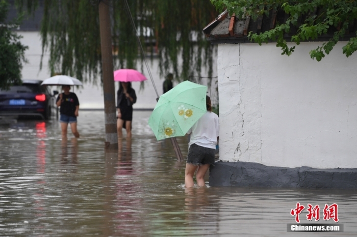 7月31日，市民行走在雨中的北京房山區(qū)瓦窯頭村。北京市氣象臺(tái)當(dāng)日10時(shí)發(fā)布分區(qū)域暴雨紅色預(yù)警信號(hào)。北京市水文總站發(fā)布洪水紅色預(yù)警，預(yù)計(jì)當(dāng)日12時(shí)至14時(shí)，房山區(qū)大石河流域?qū)⒊霈F(xiàn)紅色預(yù)警標(biāo)準(zhǔn)洪水。<a target='_blank' href='/'><p  align=