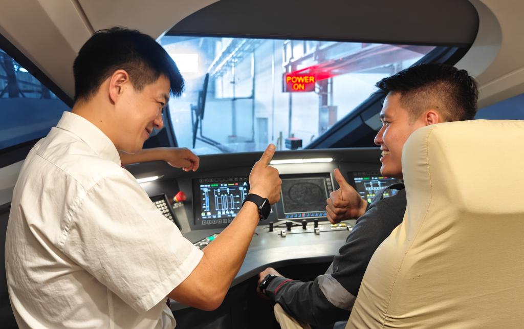 8月25日，在印度尼西亞萬隆的雅萬高鐵德卡魯爾動車所內(nèi)，中國師傅穆振（左）在向印尼火車司機塞蒂亞萬講解動車組出庫前的上電作業(yè)。
