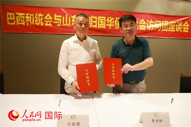 中國僑聯(lián)副主席、山東省僑聯(lián)主席李興鈺（右）與巴西和統(tǒng)會會長王俊曉簽署合作協(xié)議書。人民網(wǎng)記者 陳海琪攝