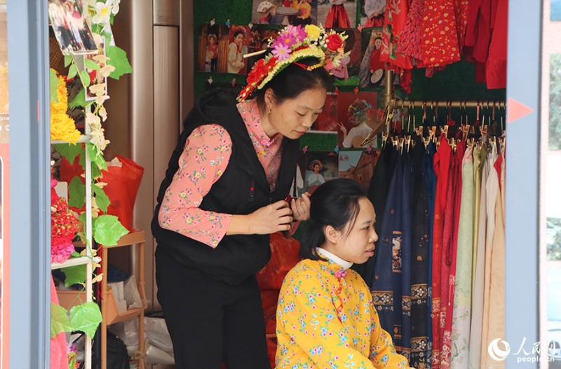 泉州府文廟附近，一名店主正為過(guò)路游客梳理頭發(fā)以佩戴“簪花圍”。人民網(wǎng) 黃東儀攝
