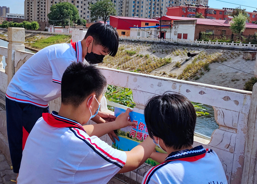 徐水小學(xué)學(xué)雷鋒志愿者在瀑河河邊張貼防溺水警示標語。 徐水區(qū)委宣傳部供圖