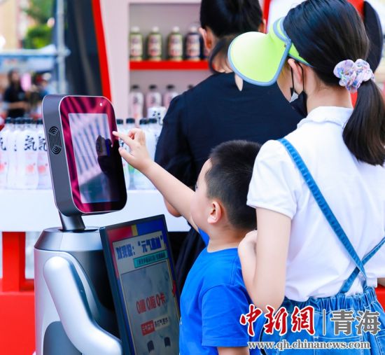 圖為一名小朋友正在和機器人“志愿者”進行互動。 沐聞 攝