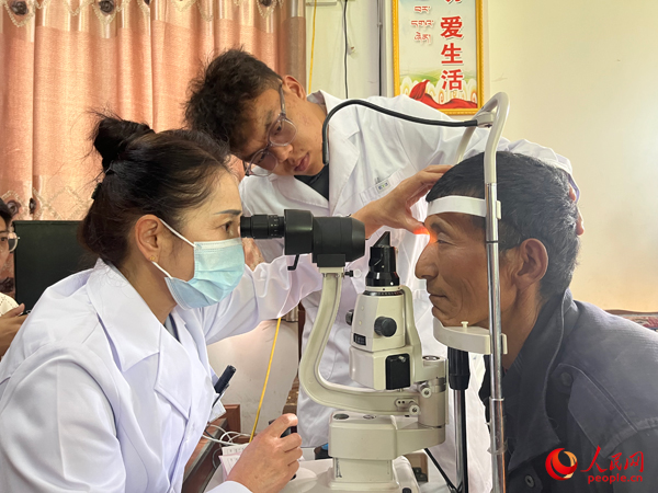 王紅英（左）和團(tuán)隊(duì)成員為達(dá)熱村村民檢查眼睛。人民網(wǎng)記者 杜燕飛攝