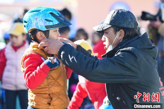 圖為拉薩市實(shí)驗(yàn)幼兒園孩子在教練的幫助下穿戴頭盔?！『闻罾?攝