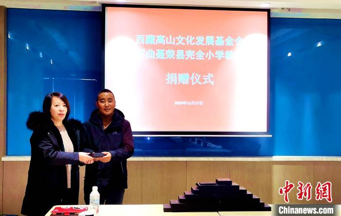 圖為西藏高山文化發(fā)展基金會(huì)理事長(zhǎng)溫麗向聶榮縣完全小學(xué)負(fù)責(zé)人捐助儀器?！∮谫e 攝