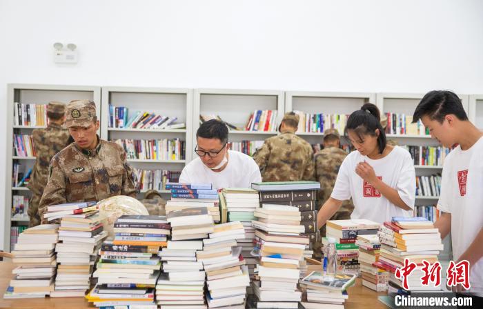 圖為志愿者們和邊防戰(zhàn)士整理圖書?！詵| 攝