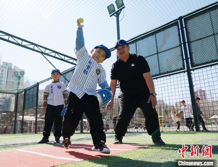 圖為來自臺灣的棒球教練劉興鴻(右)指導(dǎo)小棒球手?jǐn)S球技術(shù)?！●R銘言 攝