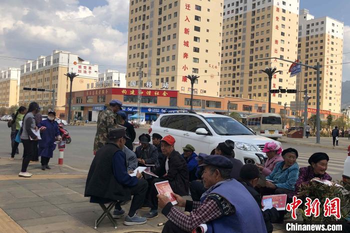 圖為會澤縣城易地扶貧搬遷安置點內，老人們聚在廣場上聊天，身后是他們的新家。　繆超 攝
