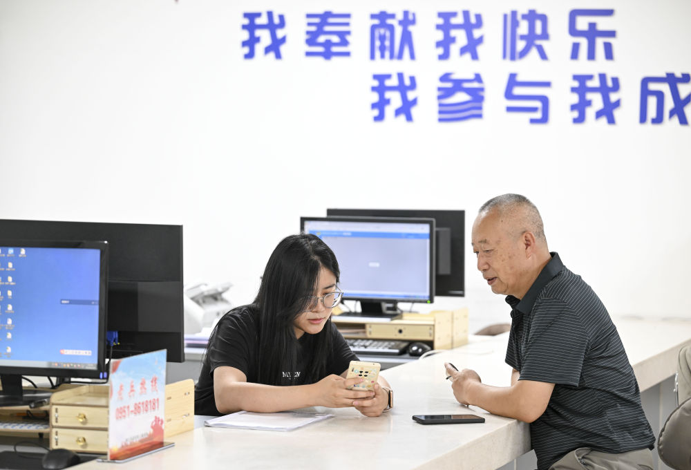 2024年6月20日，在寧夏銀川市金鳳區(qū)長(zhǎng)城花園社區(qū)黨群服務(wù)中心，工作人員幫助居民辦理業(yè)務(wù)。圖片來(lái)源 新華社