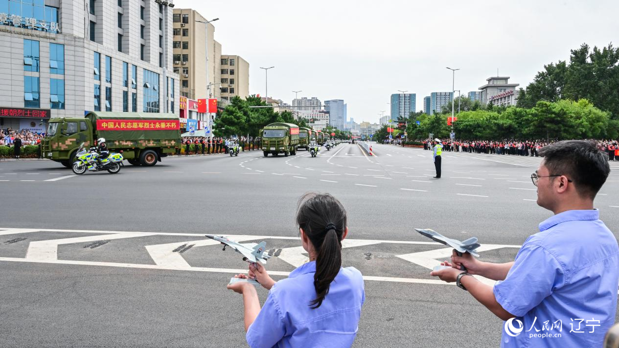 航空工業(yè)沈飛的青年技術(shù)人員拿著受閱戰(zhàn)機(jī)的模型迎接烈士遺骸。航空工業(yè)沈飛供圖