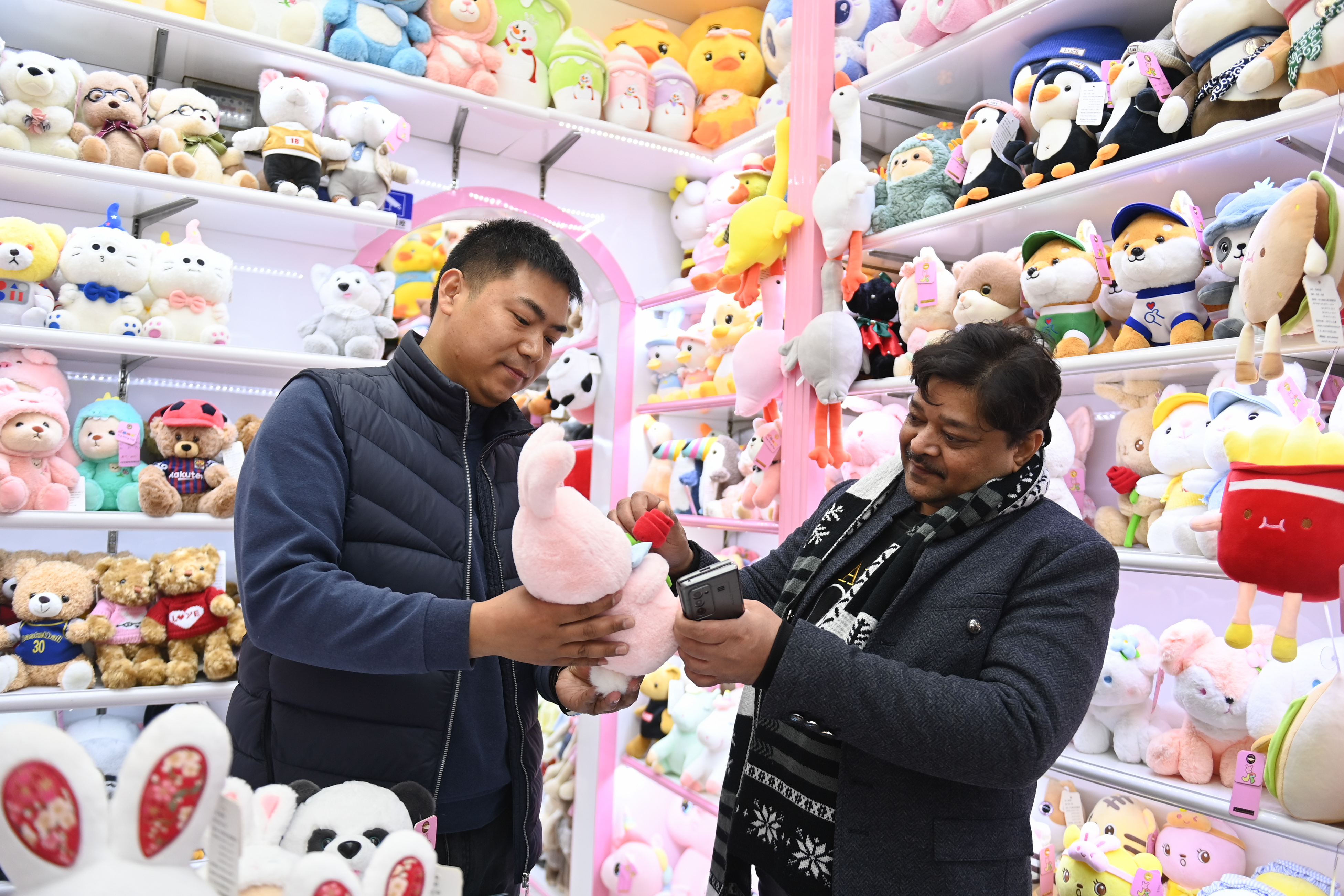 2023年2月2日，來自印度的客商（右）在義烏國際商貿(mào)城的一家玩具店鋪內(nèi)選購。