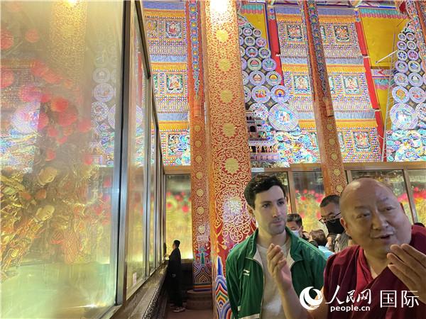 7月25日，省級(jí)非物質(zhì)文化遺產(chǎn)項(xiàng)目塔爾寺酥油花的代表性傳承人朋措堅(jiān)參（右）在塔爾寺酥油花館講解酥油花的制作過程。人民網(wǎng) 謝瑩攝
