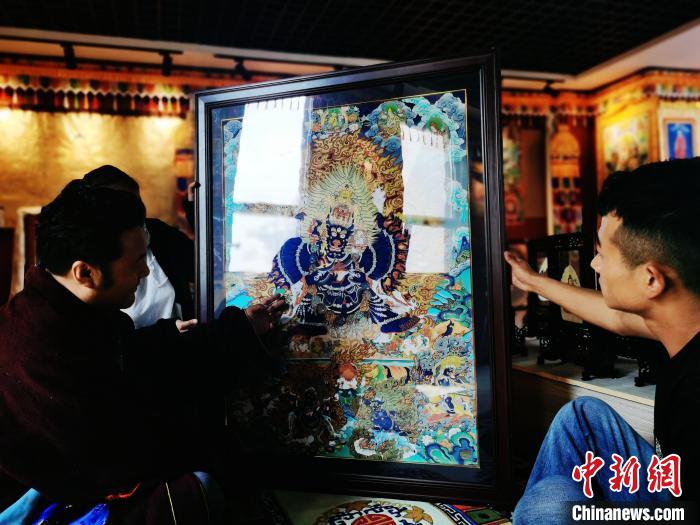 圖為久美尖措(左)與徒弟們展示唐卡作品?！?zhí)砀?攝