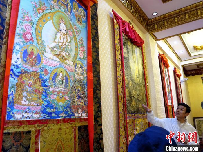 圖為完德尖措展示熱貢龍樹(shù)畫(huà)苑內(nèi)的唐卡。　張?zhí)砀?攝