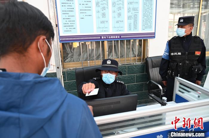 圖為移民管理警察登記完身份信息后將證件歸還給行人?！≮w朗 攝
