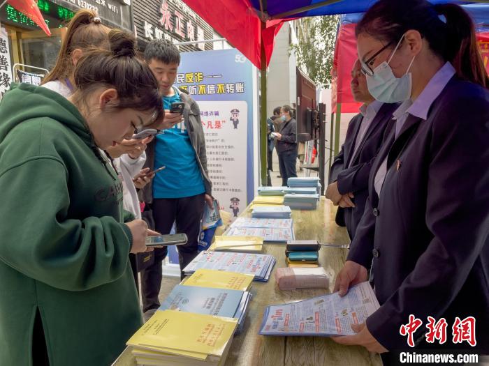 圖為工作人員正在向路過(guò)市民介紹國(guó)家反詐中心軟件的功能?！≈x牧 攝