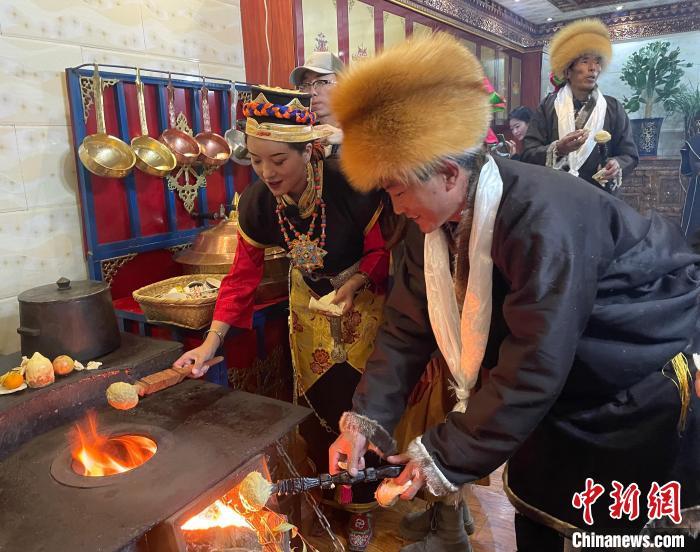圖為人們在火上烤節(jié)日美食“結達”?！∪轿木?攝