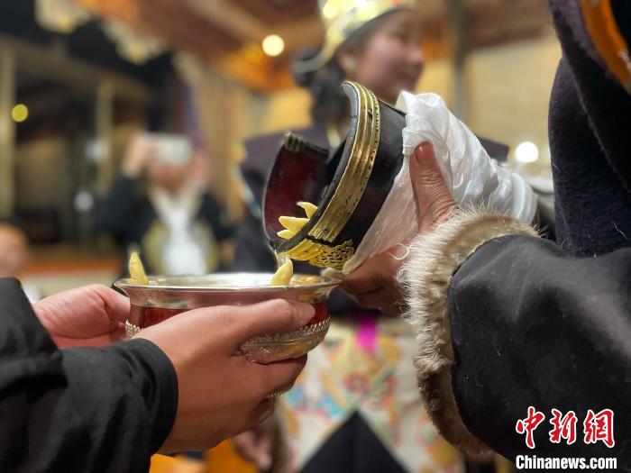 圖為主人在碗中斟滿青稞酒?！∪轿木?攝