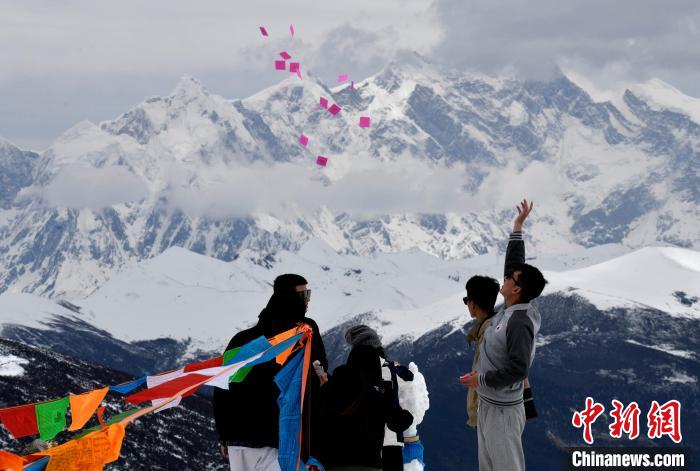 圖為5月14日，游客在西藏林芝色季拉山觀景臺拋灑“隆達”(風馬旗，藏族民眾的一種祈福方式)?！±盍?攝